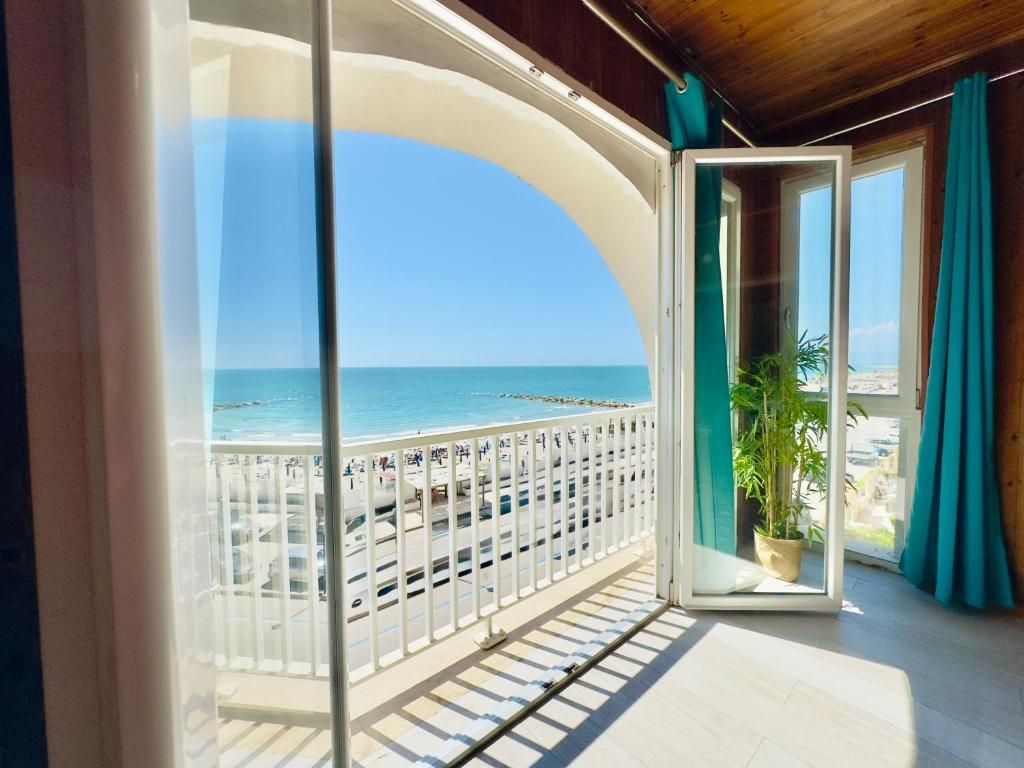 A balcony with a view of the sea, a potted plant, and a wooden ceiling.
