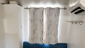 Een klein keukenhoekje met een wit aanrecht, een blauwe bank en twee houten stoelen.