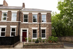 A two-story brick house with a red door, white-framed windows, and a black metal fence. - Summerhill in Newcastle (Newcastle)