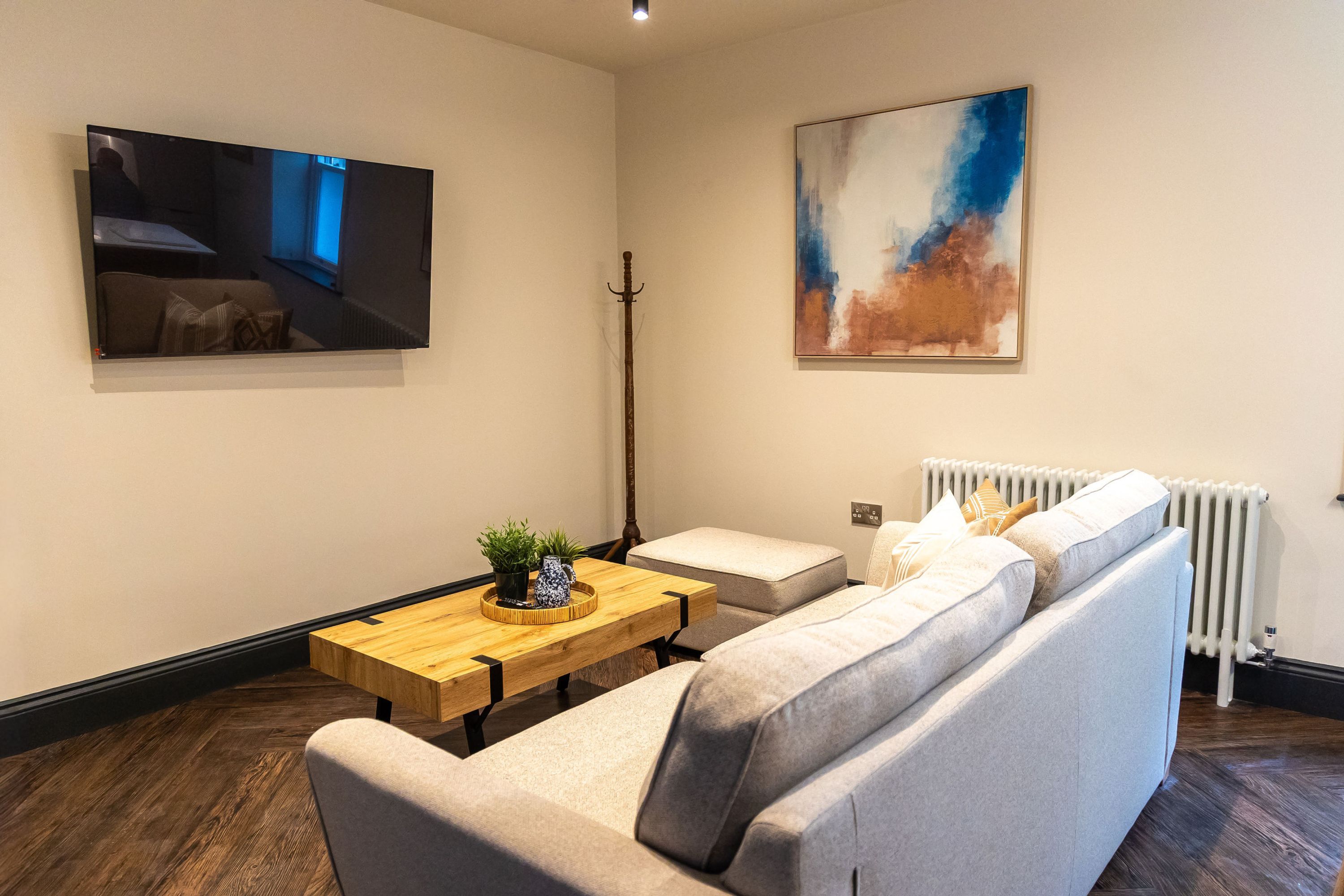 A modern living room with a sofa, a wooden coffee table, and a painting on the wall.