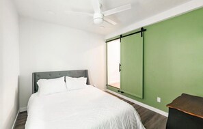 A bedroom with a bed, a ceiling fan, a green sliding door, and a small table. - Cozy 1-bedroom apartment in marvelous San Diego with AC (San Diego)