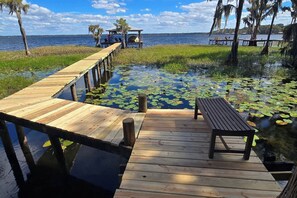 A wooden dock leading to a small gazebo with a bench and table, surrounded by water lilies. - Lake Santa Fe Getaway | Private Dock + Kayaks (Melrose)