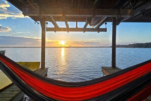 A hammock under a wooden structure with a sunset view over water. - Lake Santa Fe Getaway | Private Dock + Kayaks (Melrose)