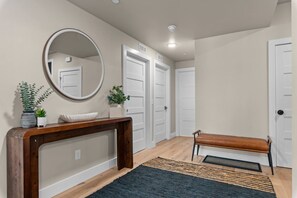 A hallway with a wooden console table, a bench, a mirror, and two doors.