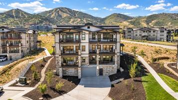 A multi-story residential building with a central courtyard, surrounded by landscaped areas and a mountainous backdrop.