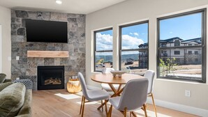 Un salon moderne doté d’une cheminée en pierre, d’un téléviseur à écran plat et d’un coin repas avec une table et des chaises.
