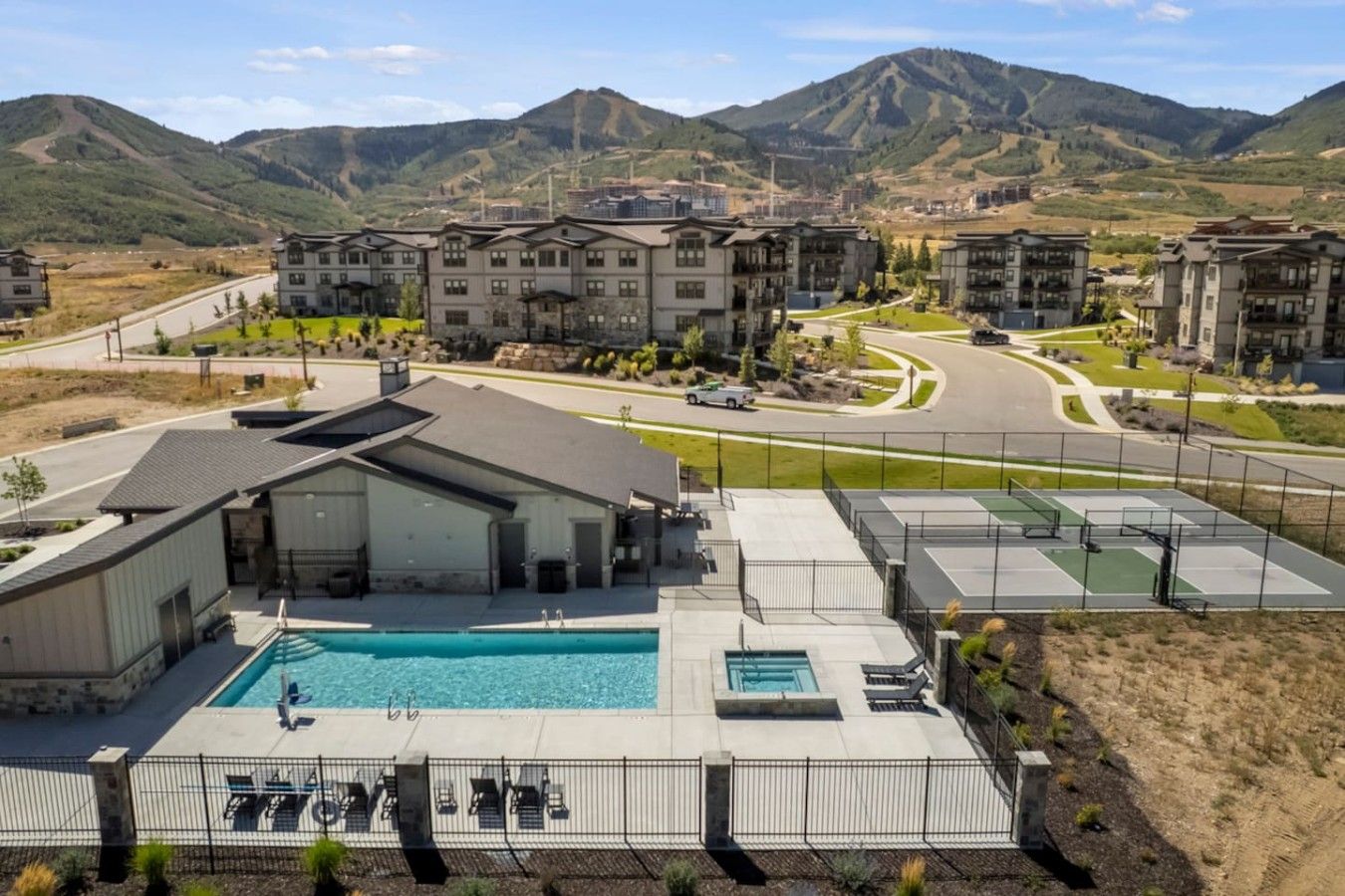 A residential area with a swimming pool, outdoor seating, and a view of mountains.