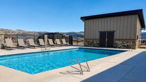 Une piscine avec des chaises longues et un bâtiment doté d’une porte.