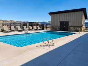 A swimming pool with lounge chairs and a building with a door. - Deer Valley East 3BR•Hot Tub•Pool•Lake View (Heber City)