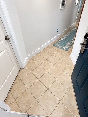 A hallway with beige tiled flooring, white walls, and a blue patterned rug. - Brilliant 1-bedroom apartment with AC in vibrant Orlando (Orlando)