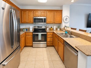 A modern kitchen with stainless steel appliances, wooden cabinets, a granite countertop, and a built-in dishwasher. - Brilliant 1-bedroom apartment with AC in vibrant Orlando (Orlando)