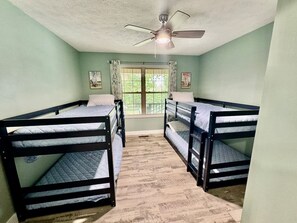 A room with bunk beds, a ceiling fan, and a window with curtains. - Stillwater Cottage at Norfork Lake (Mountain Home)