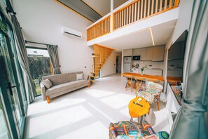 A modern interior with a sofa, dining table, chairs, and a staircase.