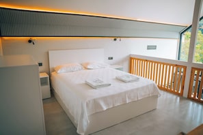 A modern bedroom with a large bed, a nightstand, a bedside table, and a view of the outdoors through a window. - Lavender Villas Sapanca (sapanca)