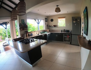 A modern kitchen with a central island, built-in appliances, and a view to the outdoors. - Creole Villa in a Tropical Garden - 3 Bedrooms & 2 Bathrooms (Sainte-Anne)