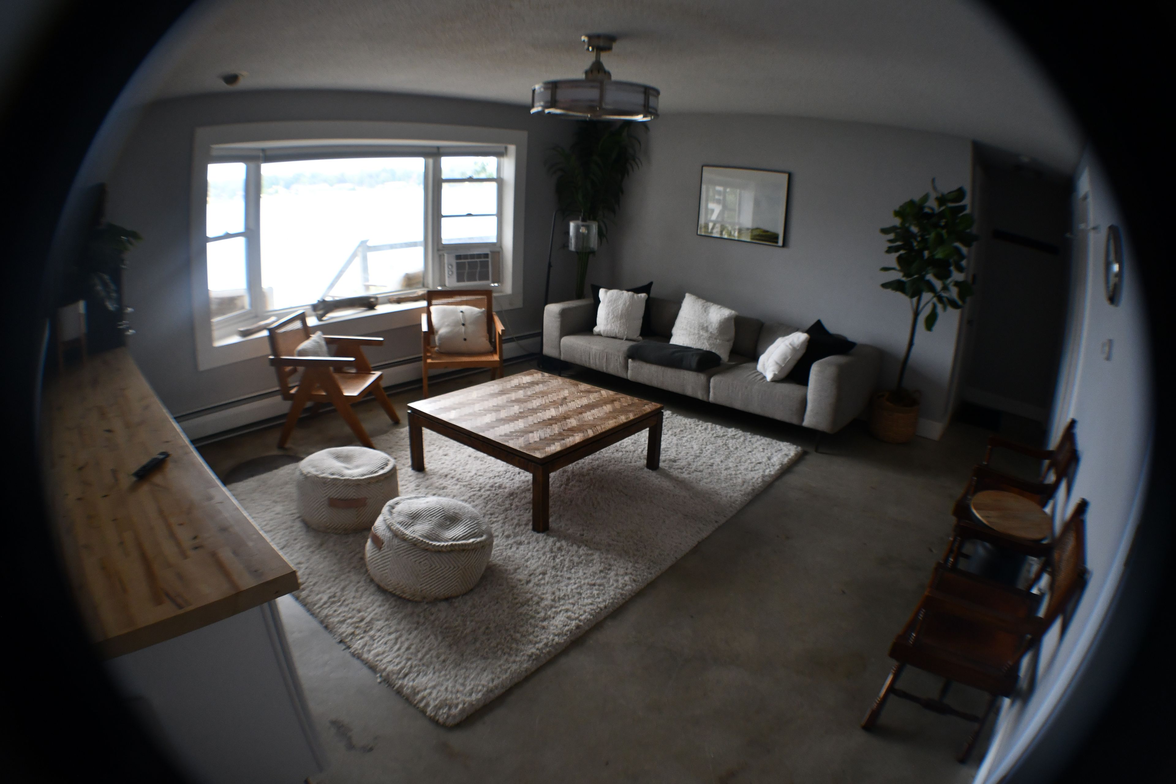 A living room with a sofa, coffee table, and chairs. There is a window providing natural light.