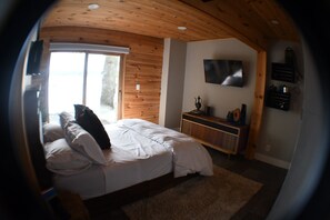 Une chambre à coucher avec un lit, un téléviseur fixé au mur et une fenêtre.