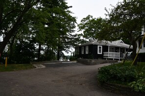 A two-story house with a porch and a driveway leading to a dock. - 5BR All-Sports Lakehouse · Hot Tub + Pontoon · Portage (Portage)