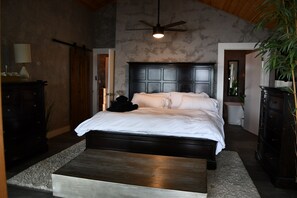 A bedroom with a large bed, a ceiling fan, and a wooden headboard. - 5BR All-Sports Lakehouse · Hot Tub + Pontoon · Portage (Portage)