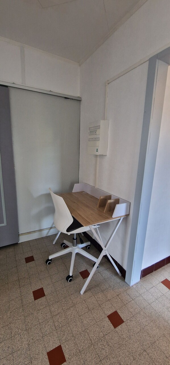 A small office space with a desk, chair, and a whiteboard on the wall.