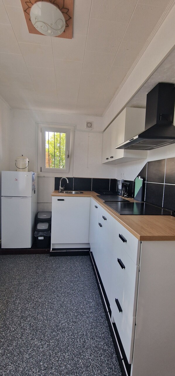 A kitchen with white cabinets, a black countertop, and a window with a view of trees.
