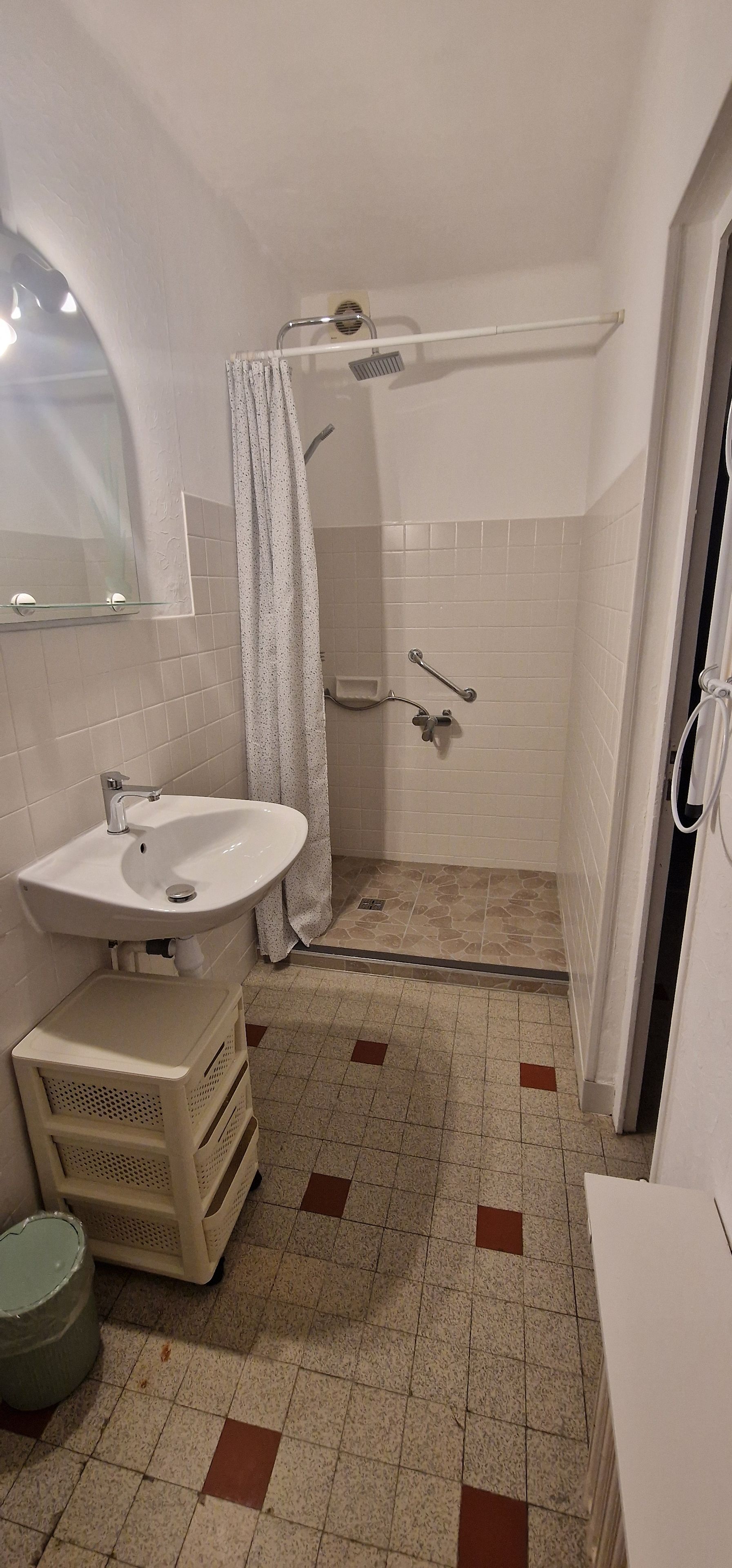 Ein Badezimmer mit Waschbecken, Dusche und Fliesenboden.