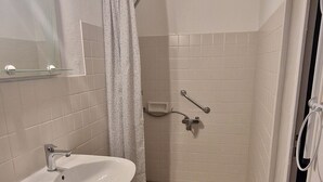 Baño con lavamanos, ducha y piso de baldosas.