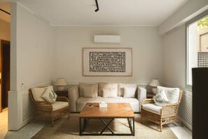 A living room with a sofa, two armchairs, a coffee table, and a wall-mounted air conditioning unit. - Solé Mare Rooftop Studio I Nesty Hospitality (Al Maadi)