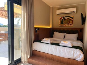 A hotel room with a bed, a window with curtains, an air conditioning unit, and a wall-mounted artwork. - Solé Mare Rooftop Studio I Nesty Hospitality (Al Maadi)