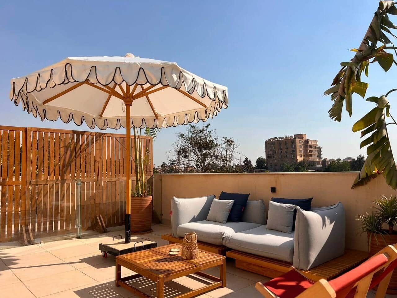Une terrasse sur le toit, avec un canapé, une table, un parasol et une clôture en bois.