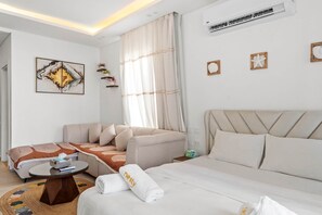 Une chambre d’hôtel moderne équipée d’un lit, d’un canapé, d’une petite table et d’un climatiseur fixé au mur.