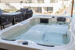 A hot tub with a control panel, surrounded by outdoor furniture and a pool. - Maraya Hideaway Private Jacuzzi| Nesty Hospitality (Second Hurghada)