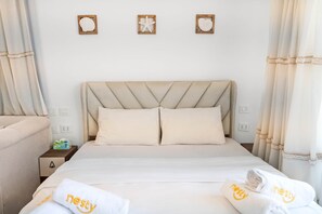 Ein Hotelzimmer mit einem Bett, zwei Kissen, einem Nachttisch und einer Wand mit drei gerahmten Bildern.