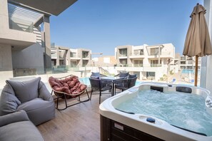Une terrasse sur le toit équipée d’un jacuzzi, d’un espace salon et offrant une vue sur les bâtiments environnants.