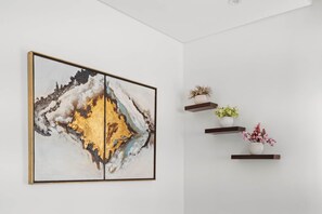 Ein modernes Interieur mit einem großen, abstrakten Gemälde und drei Regalen mit Topfpflanzen.