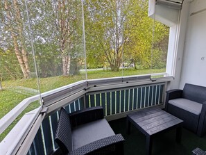 A covered outdoor seating area with a view of a grassy park and trees.