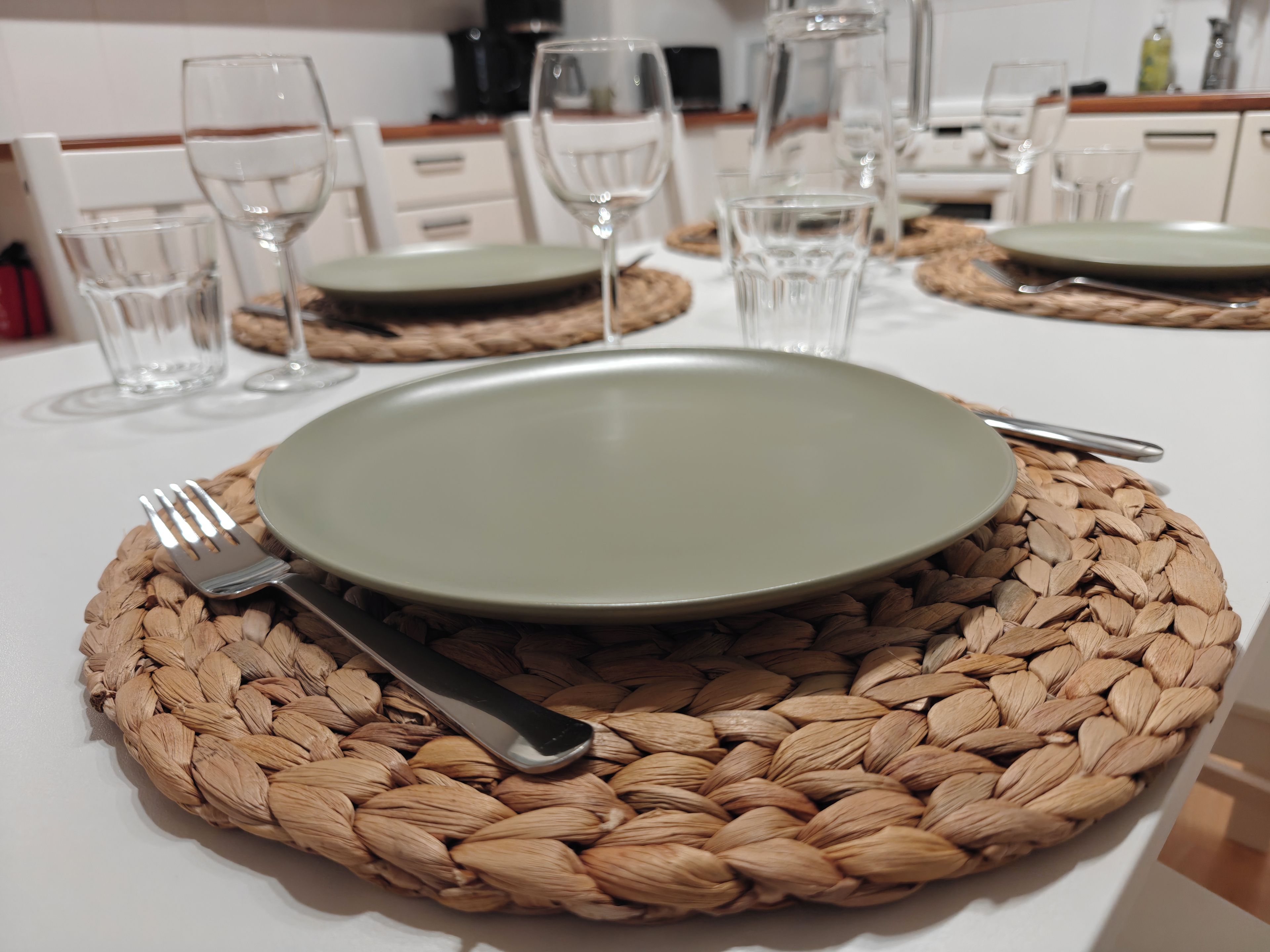 Une table à manger dressée avec une assiette, une fourchette et un couteau, le tout posé sur un set de table en fibres tressées.
