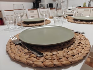A dining table set with a plate, fork, and knife on a woven placemat.