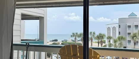 A balcony with a view of the ocean and a parking area.