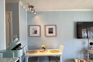 Ein Essbereich mit einem weißen Tisch, zwei gerahmten Bildern an der Wand und einer Deckenleuchte.