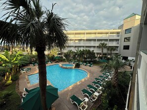 A pool area with multiple lounge chairs and a palm tree. - Steps to Beach-Ocean View-1bd1ba- Sleeps 5-Pool (Galveston)