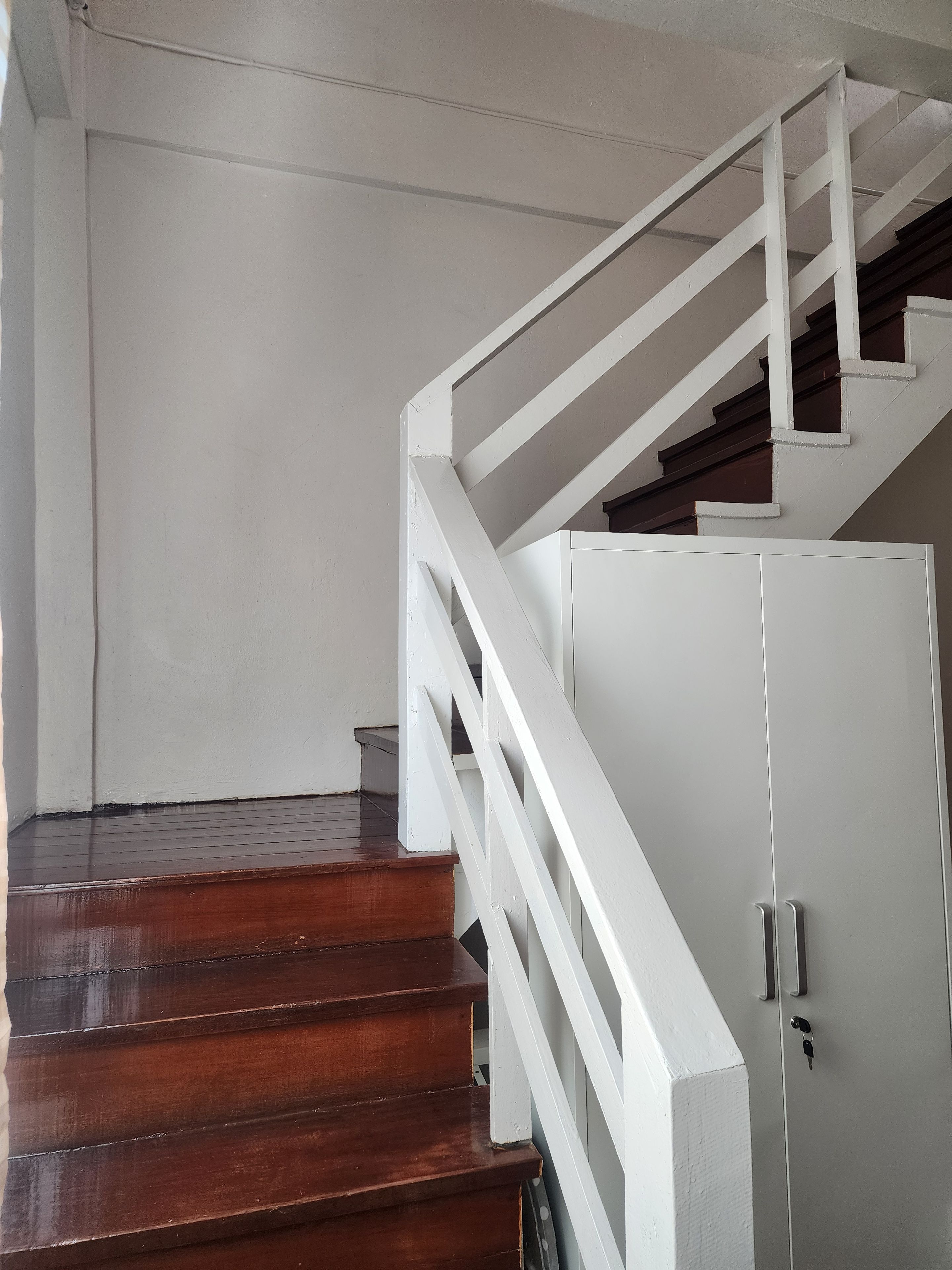 A wooden staircase with white railings leading to a landing.