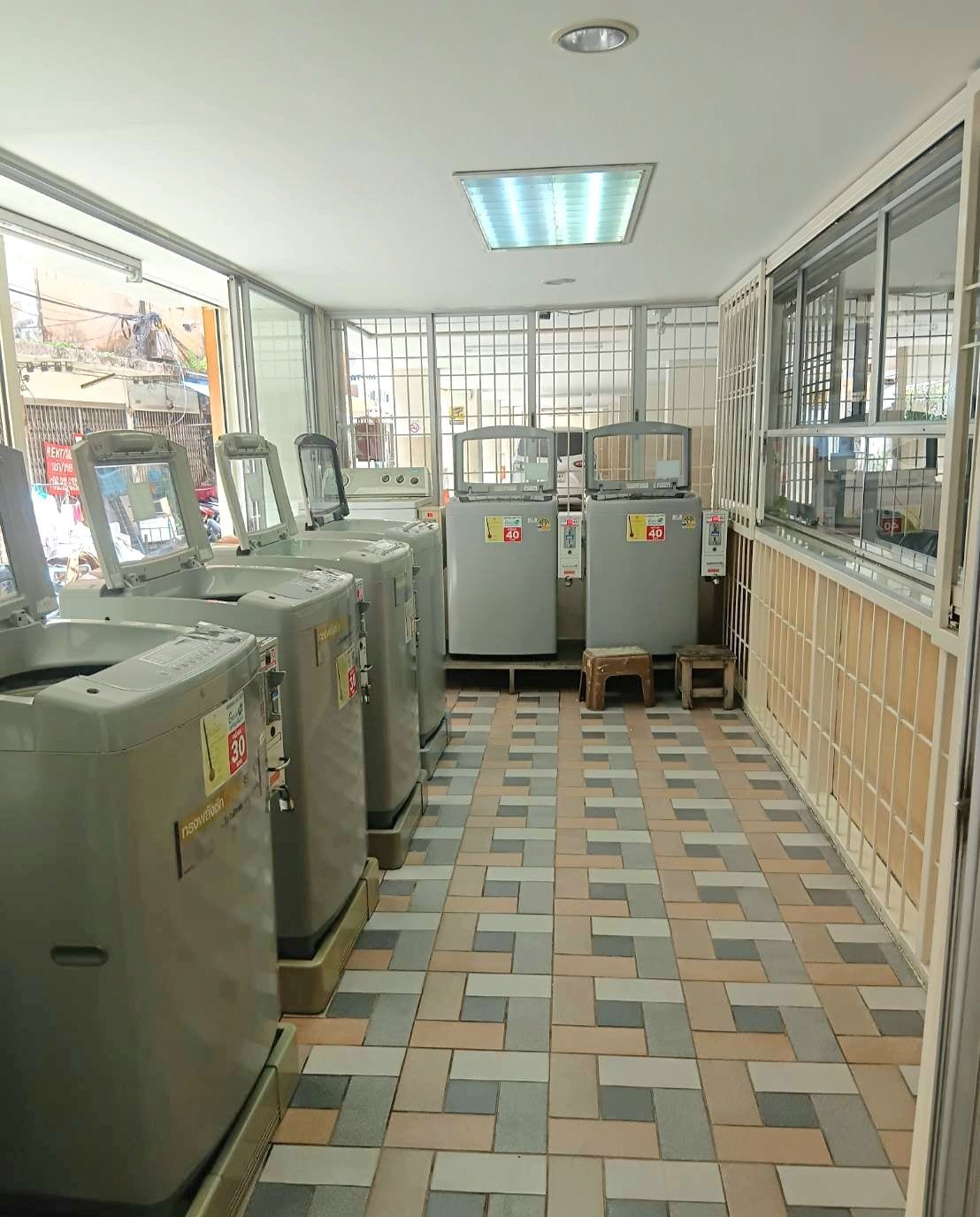 A room with a tiled floor, large industrial machines, and barred windows.
