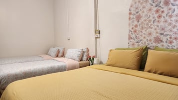 A room with two single beds, one with a floral-patterned bedspread and the other with a solid yellow bedspread.