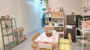 A compact kitchen with a dining table, chairs, and a small refrigerator.