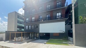 Un edificio moderno con tejado plano, varios balcones y una zona de estar exterior cubierta.