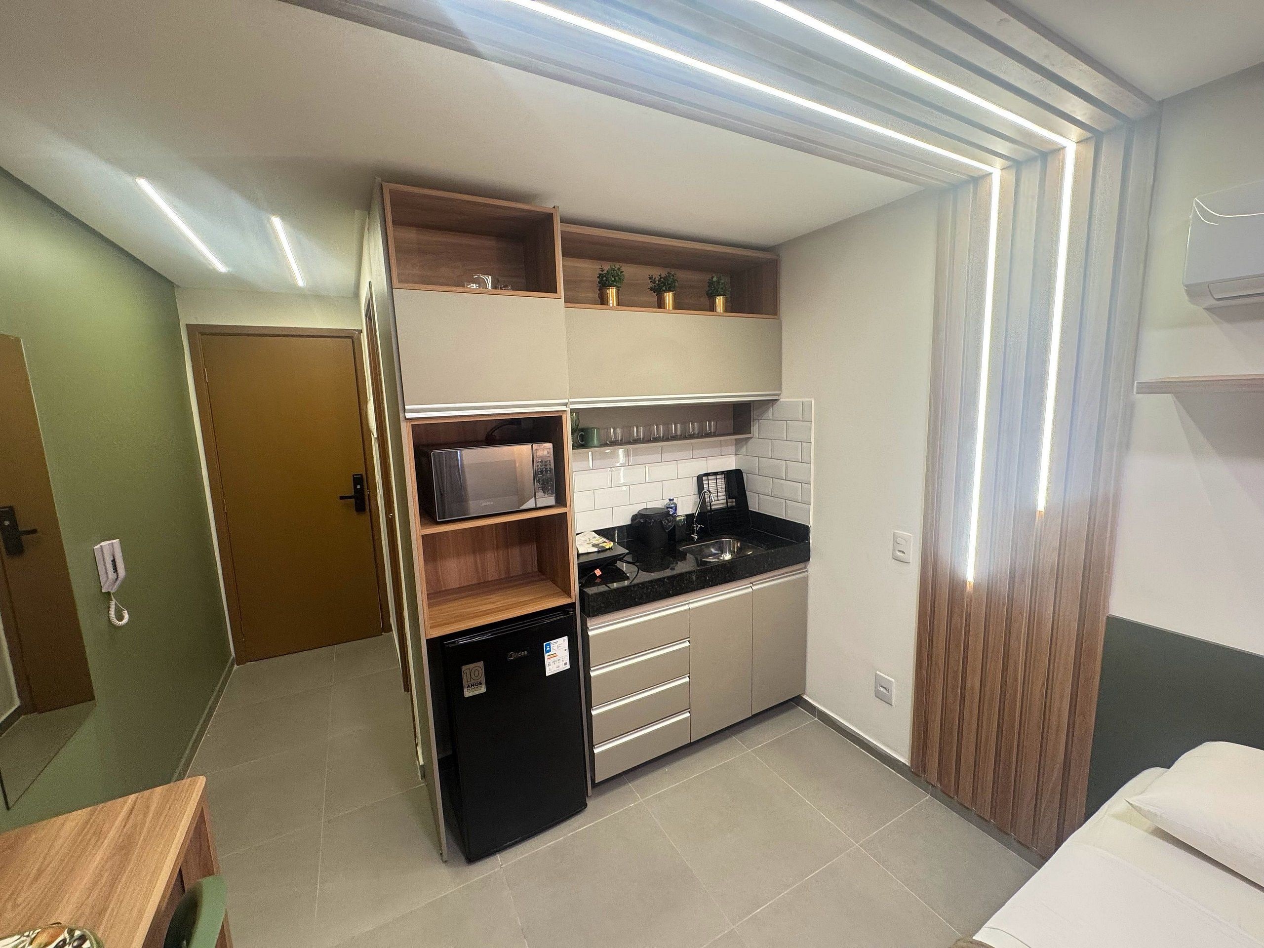 Una cocina compacta con electrodomésticos integrados, un lavamanos y una encimera.