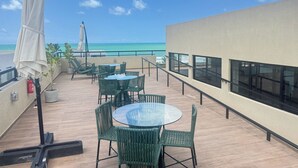 Una terraza con mesas y sillas, con vista a una playa.
