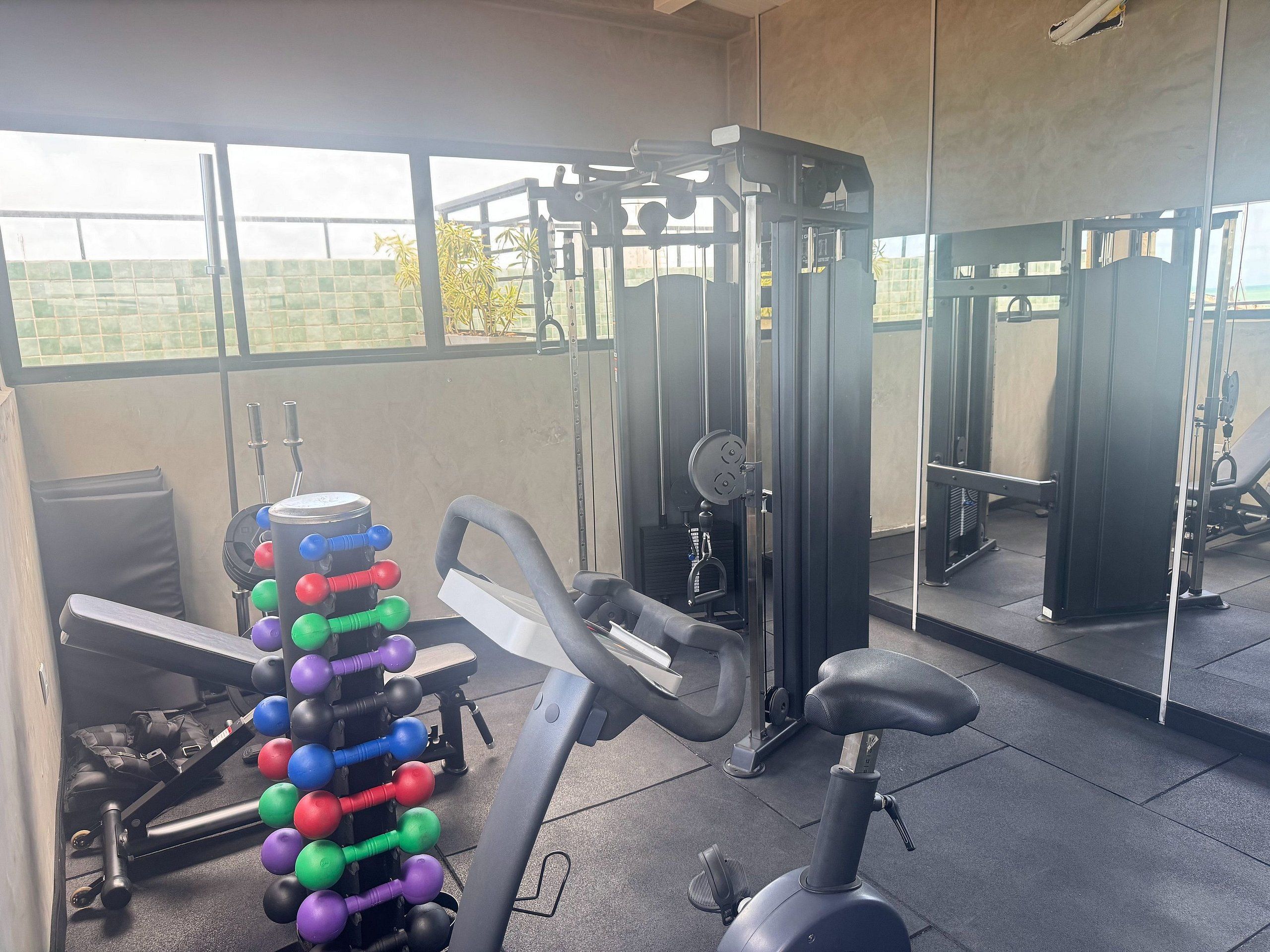 A gym with exercise equipment, a bench, and a mirror.