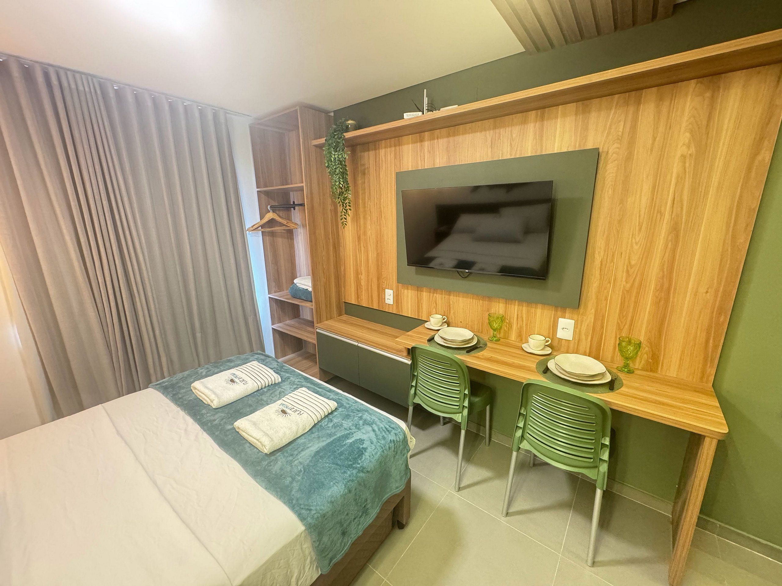 Une chambre d’hôtel comprenant un lit, un bureau, deux chaises, une télévision et une armoire.
